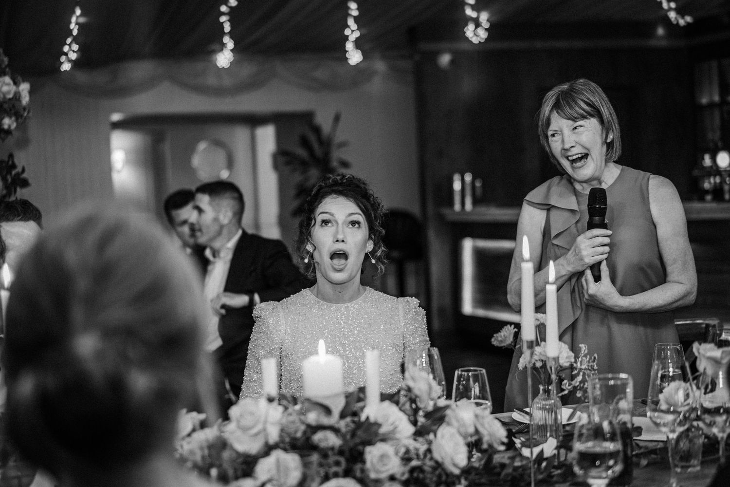 Wedding guests laughing and enjoying themselves at an elegant candlelit reception dinner.