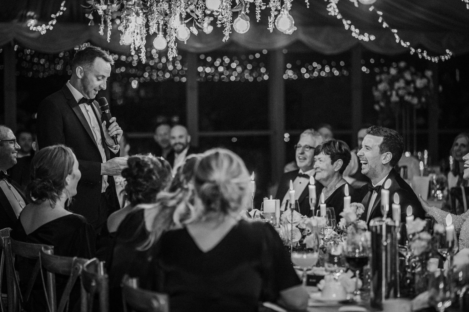 Black and white candid shots of guests socializing and dining at an elegant indoor wedding reception.