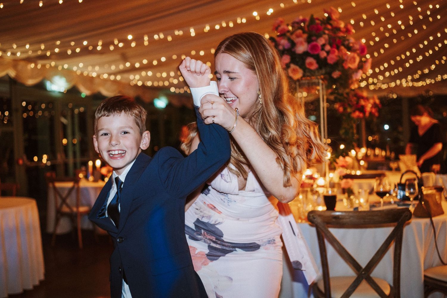 Couples dancing together at a wedding reception under romantic string light decorations.