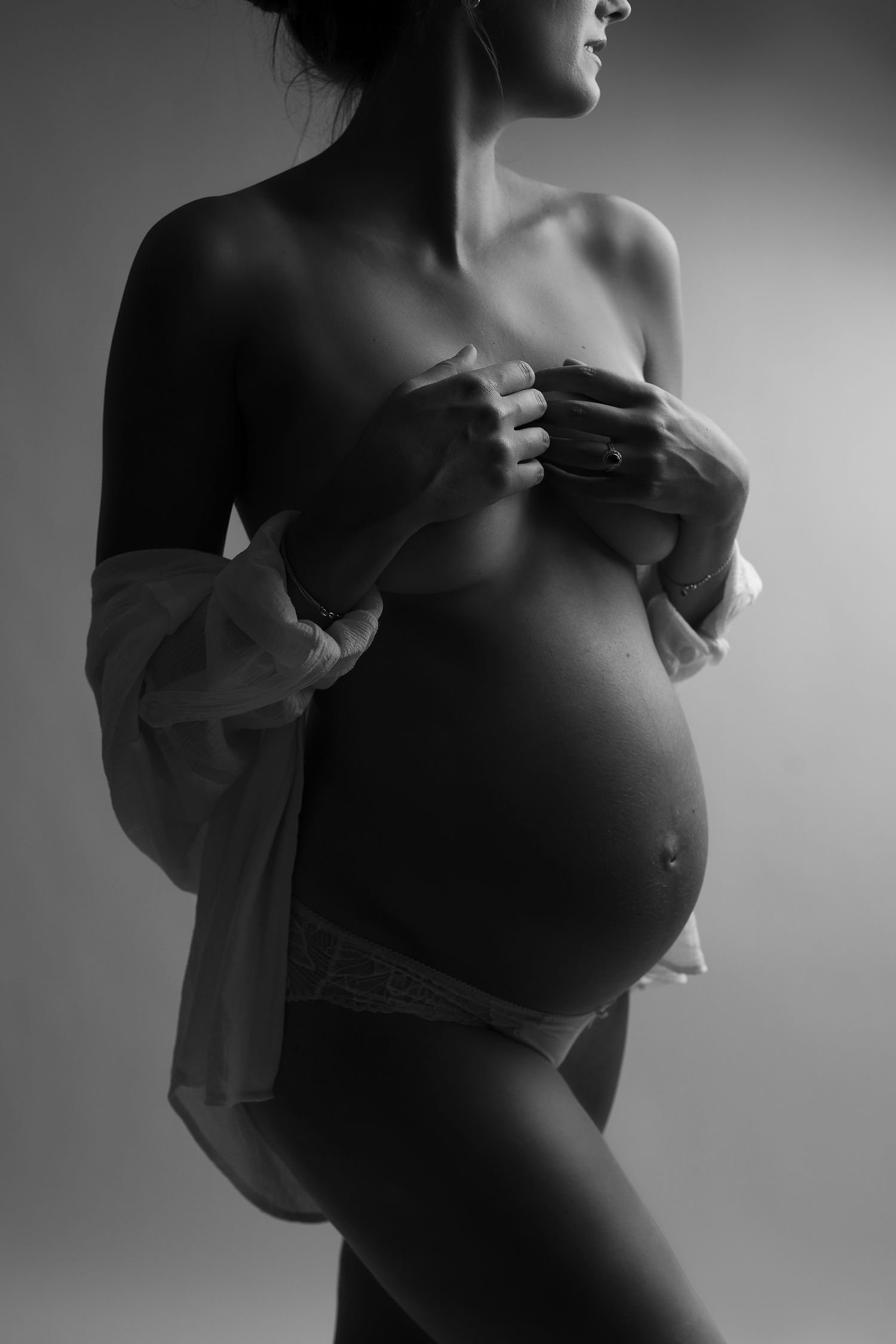 Artistic black and white maternity photography series showing silhouette of pregnant woman in flowing fabric.