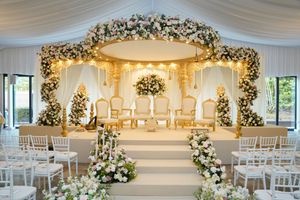 Elegant wedding venue decorated with white floral arches, draped fabric, and glowing chandeliers for a luxurious ceremony.