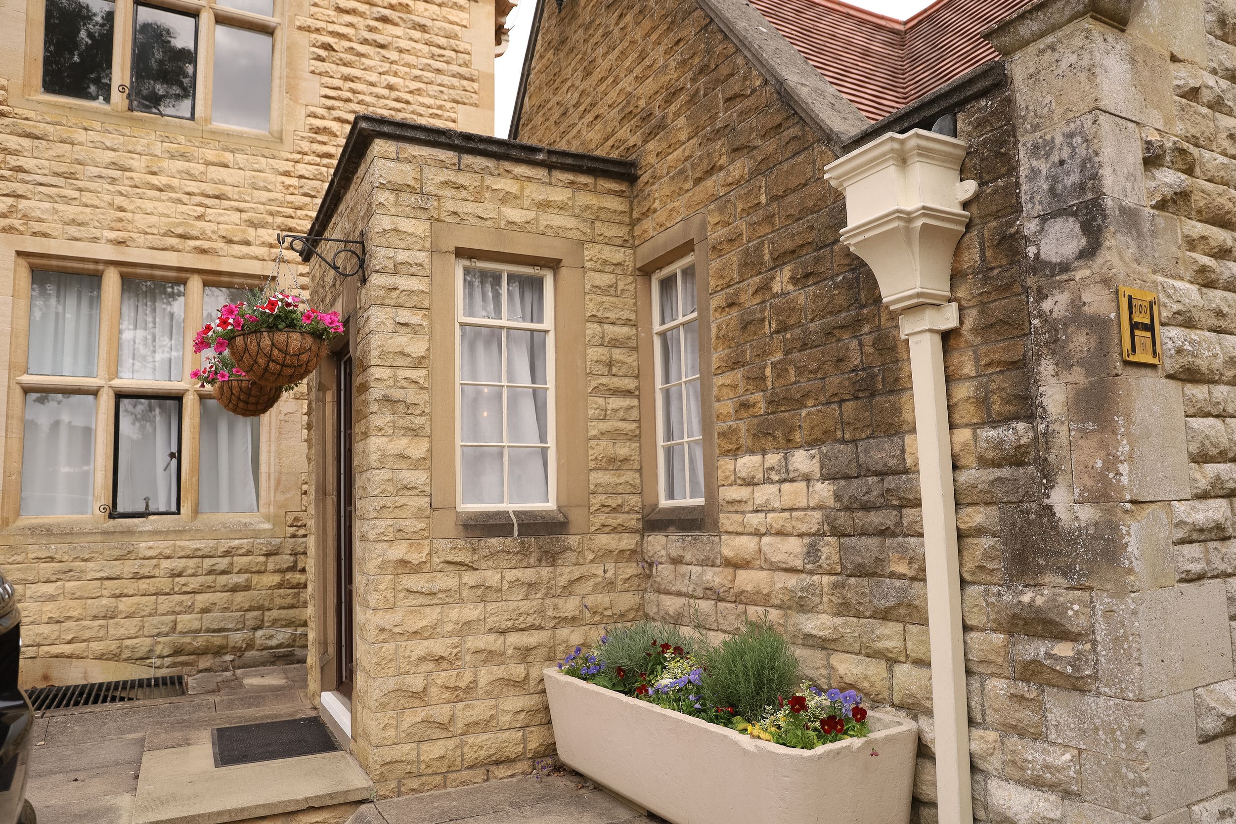 Historic stone building exterior with arched windows and doorways featuring traditional English architecture and flower boxes.