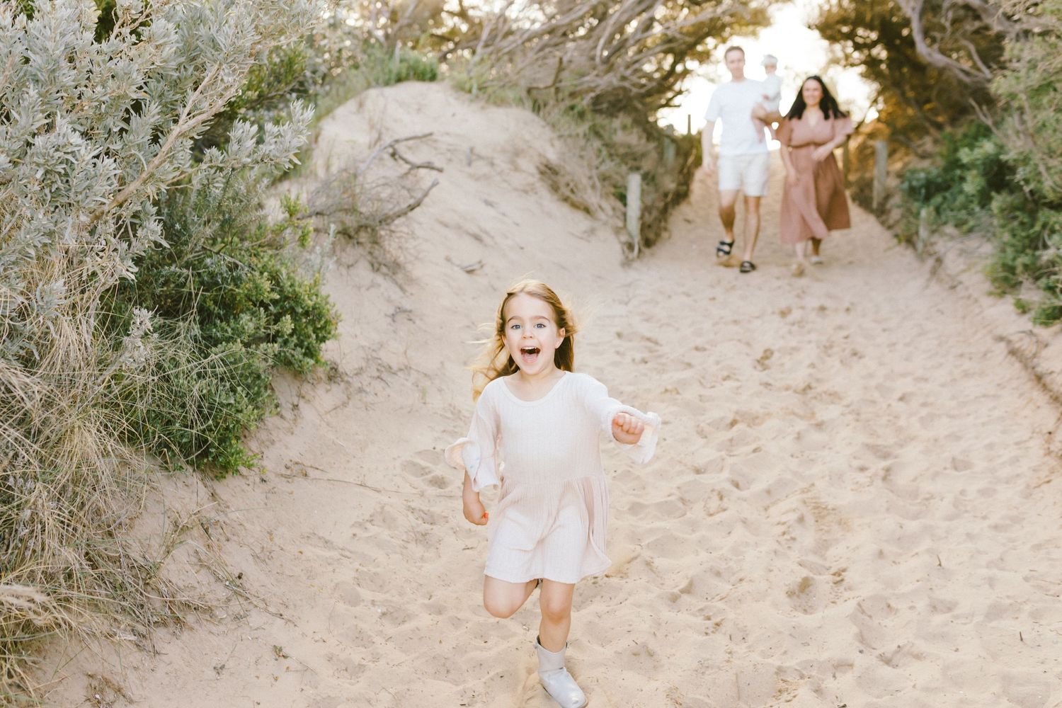 A series of seven photos showing a child walking down a sandy path through coastal vegetation and dunes.