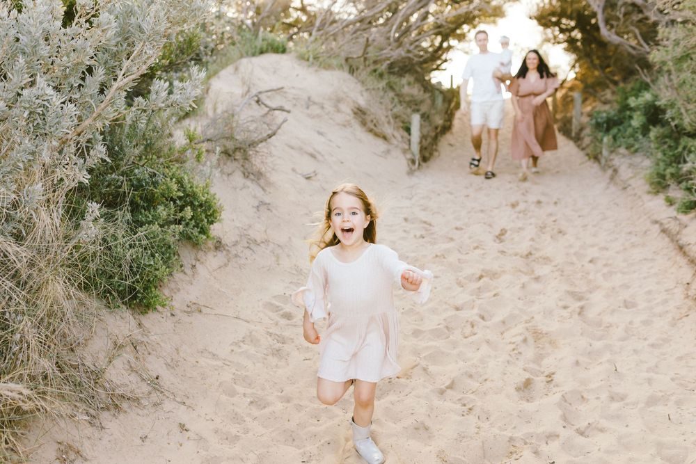 A series of seven photos showing a child walking down a sandy path through coastal vegetation and dunes.