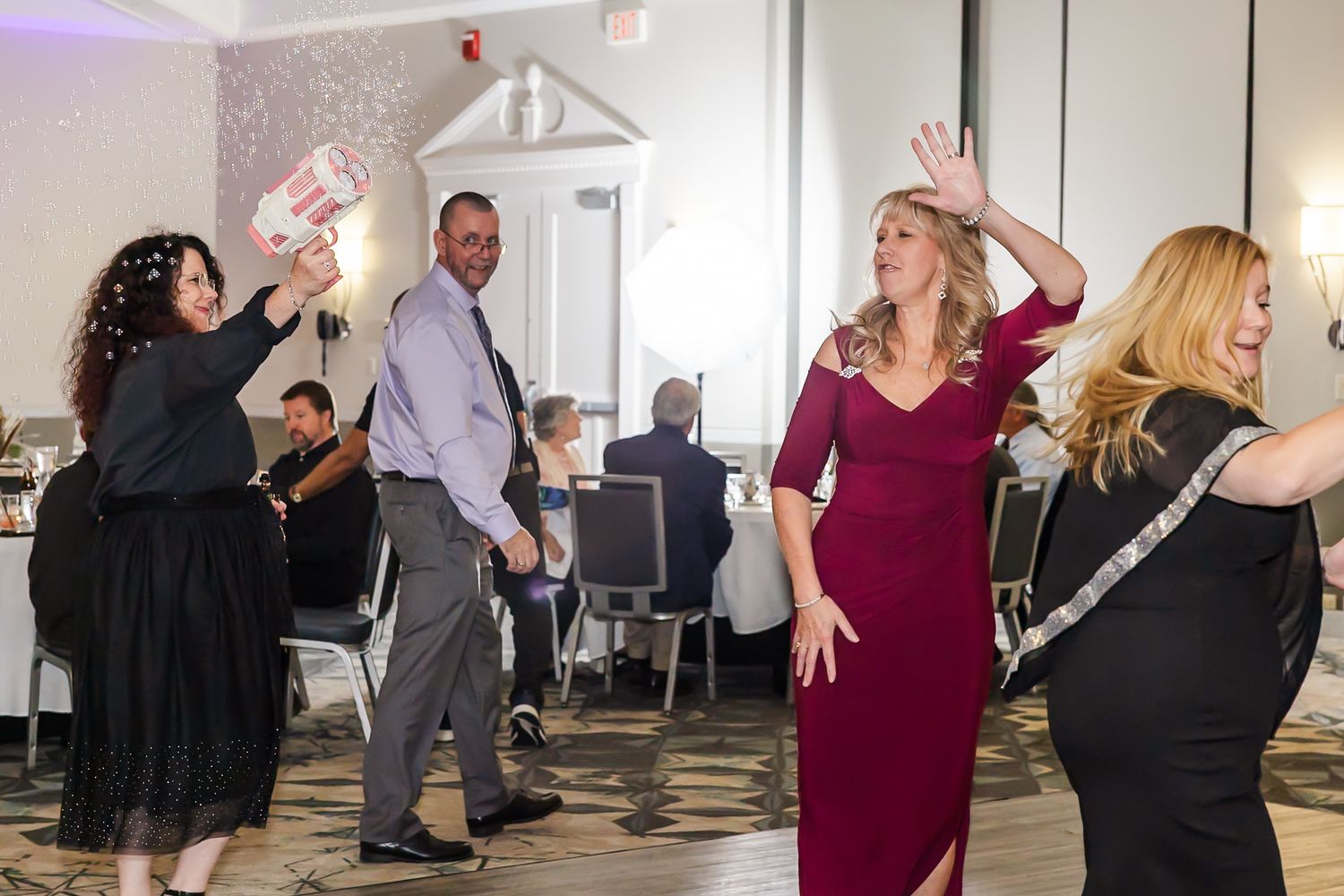 People dancing and socializing at a lively indoor party or gathering with bright lighting.
