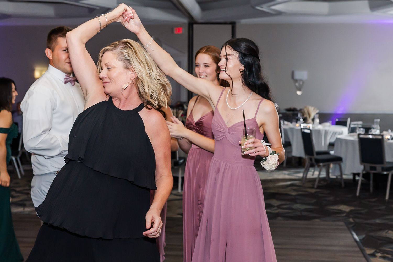 Wedding party members dancing and celebrating during a lively reception.