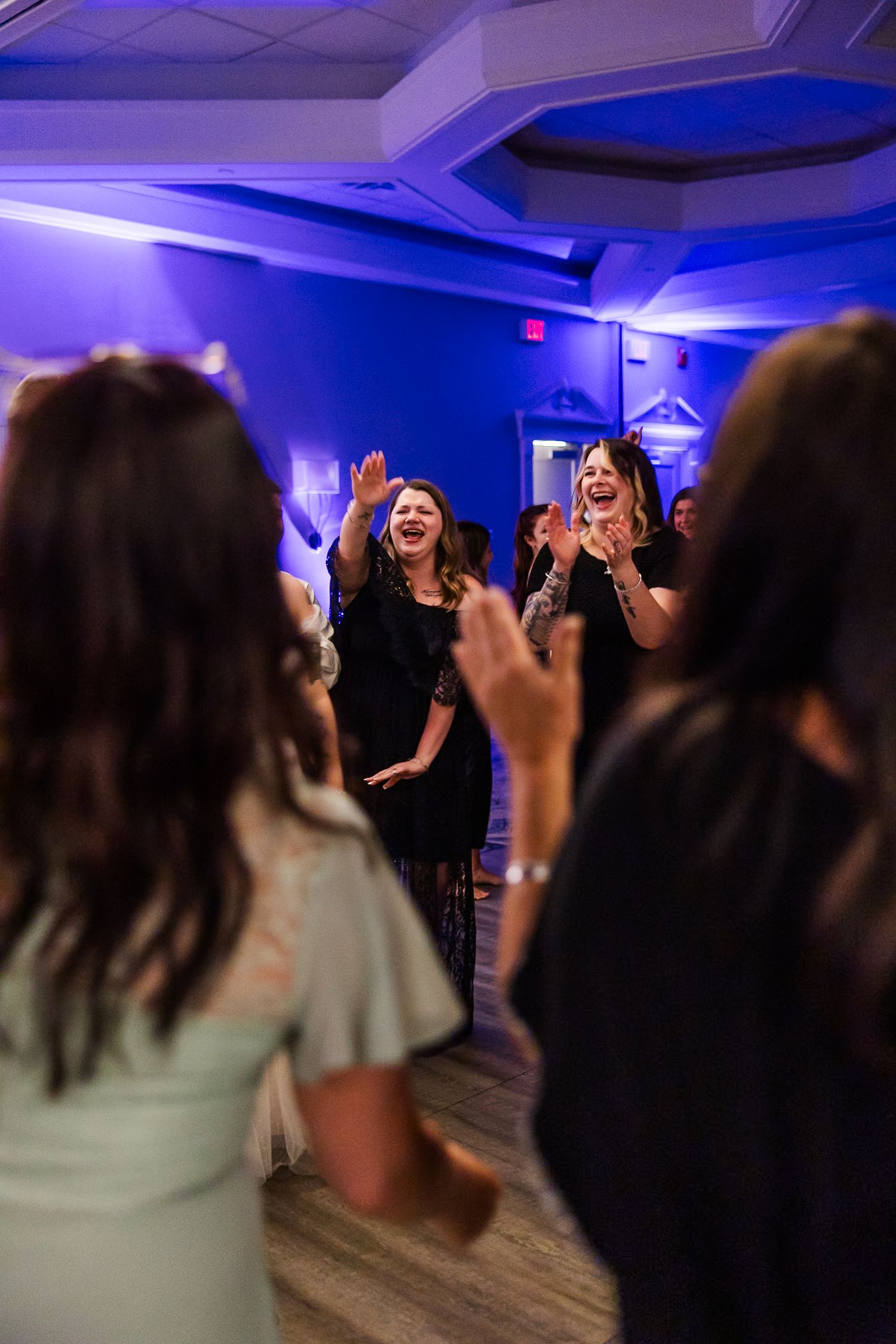 A lively dance party scene with people celebrating under blue mood lighting in an indoor venue.