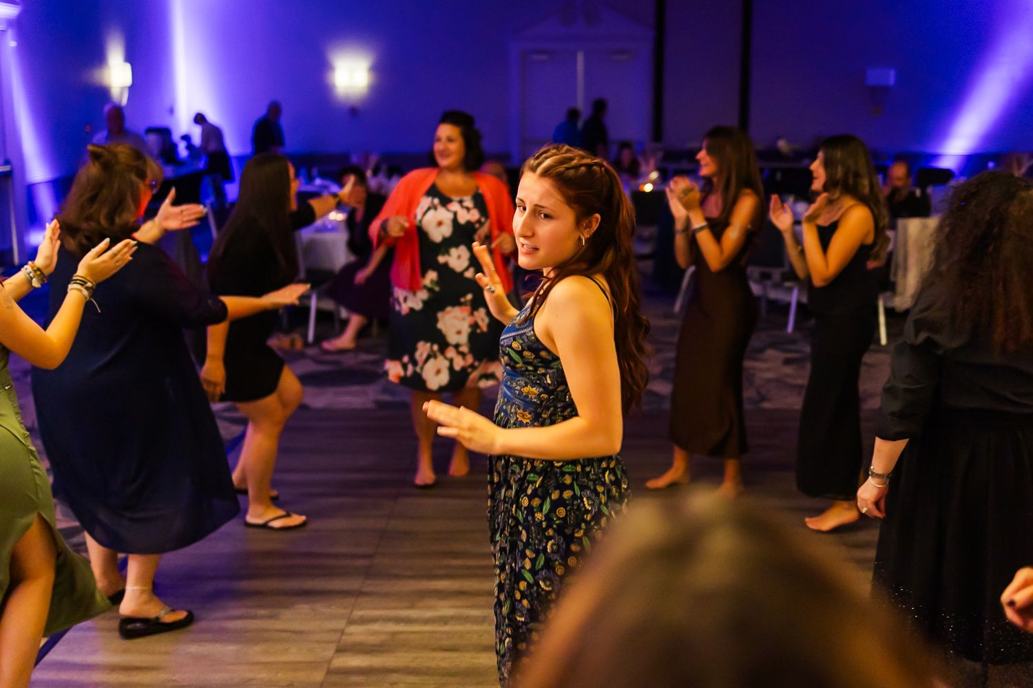 Dance floor filled with wedding guests celebrating under purple lighting in an elegant venue.