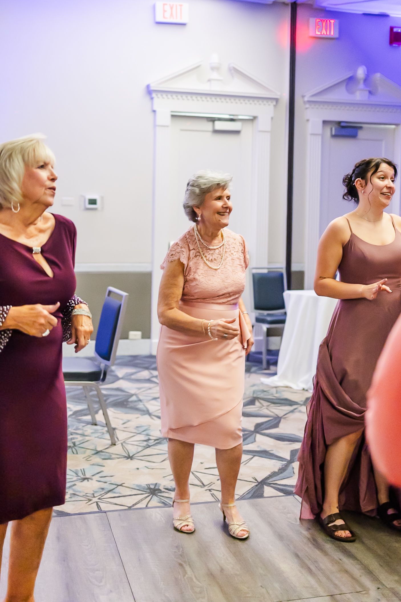 Group enjoying themselves at a formal event in elegant dresses on a dance floor.