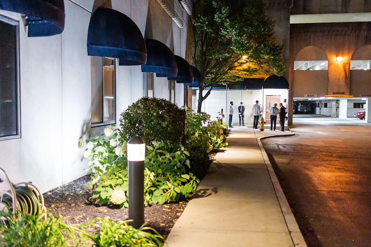 Illuminated walkway at night with modern architectural elements and landscaping creates an inviting atmosphere.