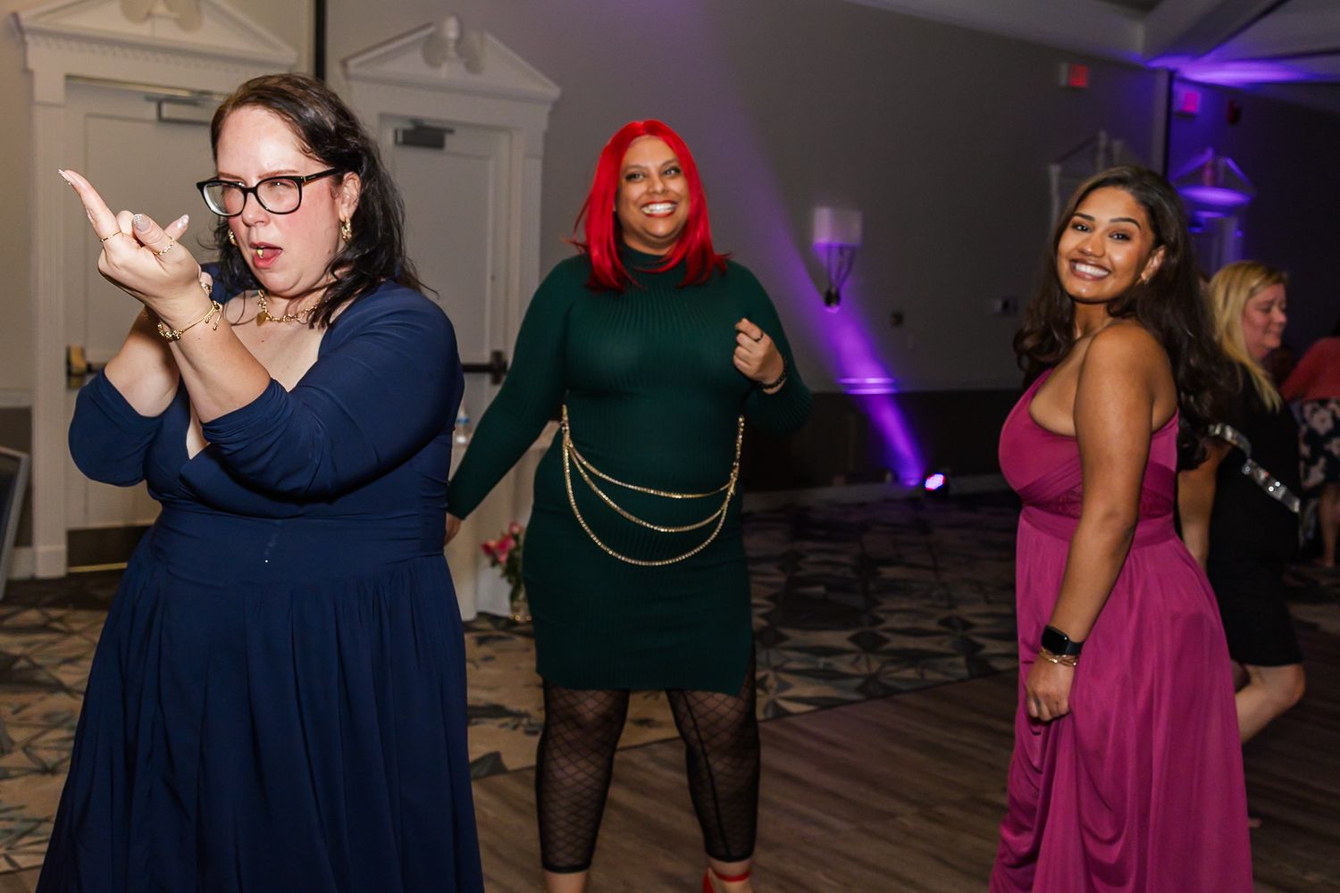 People enjoying a lively dance party in an event space decorated with purple mood lighting.