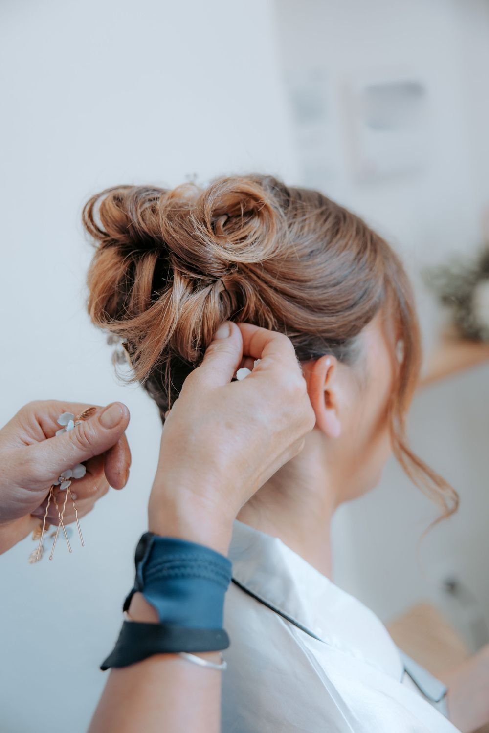 Hairstyling process showing hands creating an elegant updo for a special occasion. Domaine la Plume photographe mariage