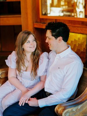 A romantic couple sitting close together on a couch sharing intimate moments in warm indoor lighting.