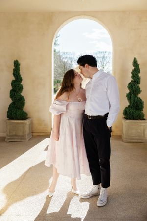 A romantic dance sequence between a couple in white outfits captured in a Mediterranean-style archway setting.