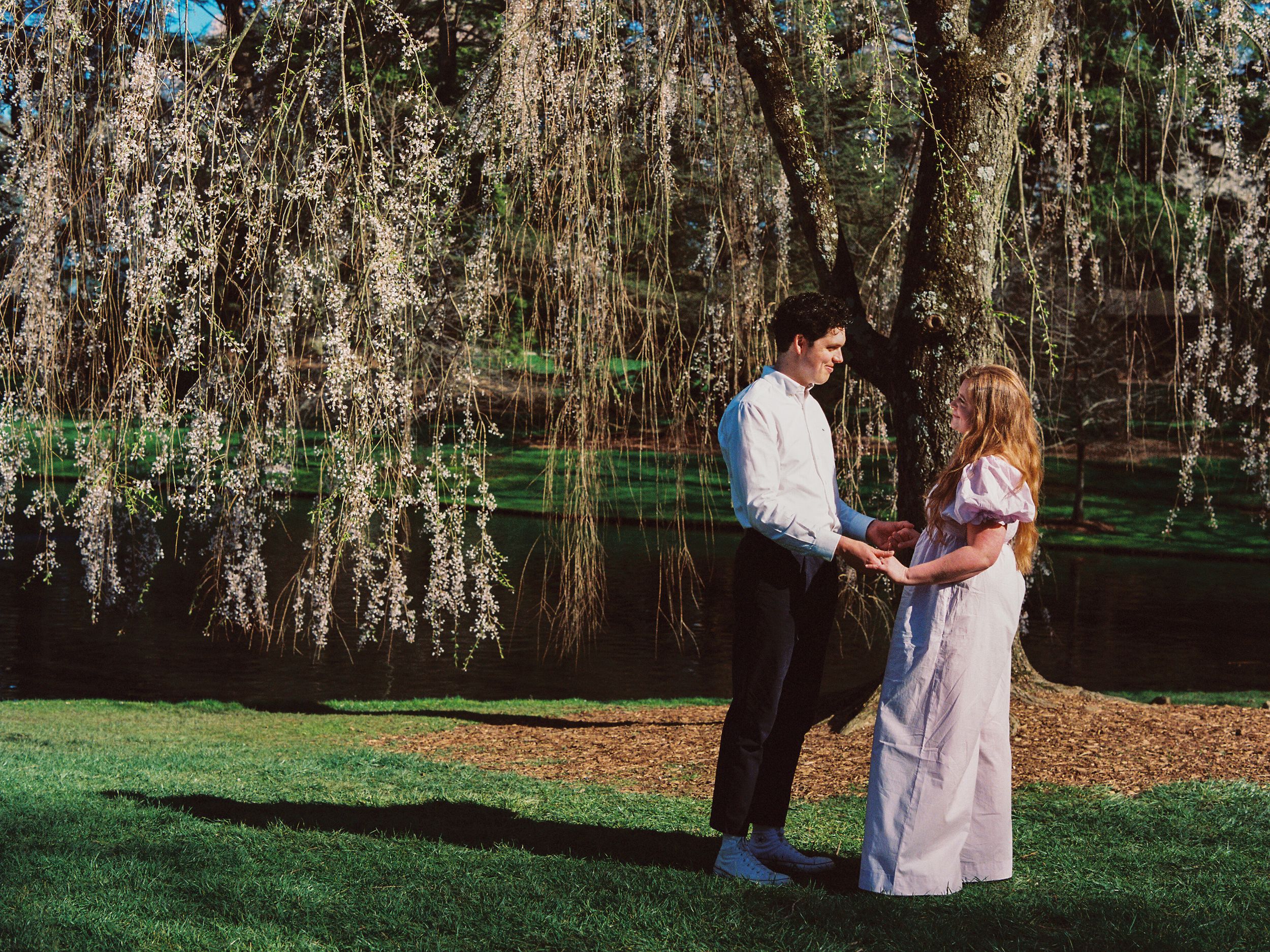 A romantic moment between a couple embracing under Spanish moss draped trees in a lush garden setting.