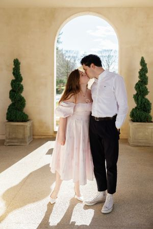 A series of romantic engagement photos showing a couple in white attire against a light stone colonnade backdrop.