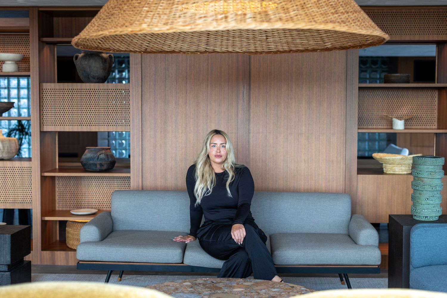 Interior lounge scene with retro mid-century furniture, large woven pendant lamp, and wood paneled walls.