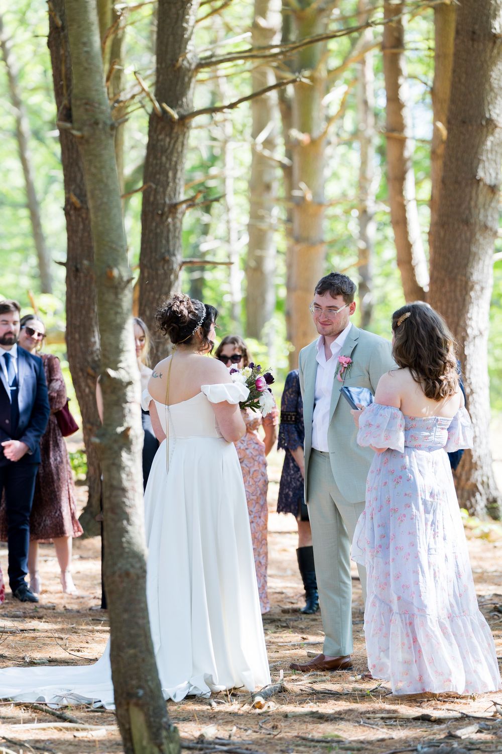 Wedding party photographed among tall pine trees in summer formal wear.