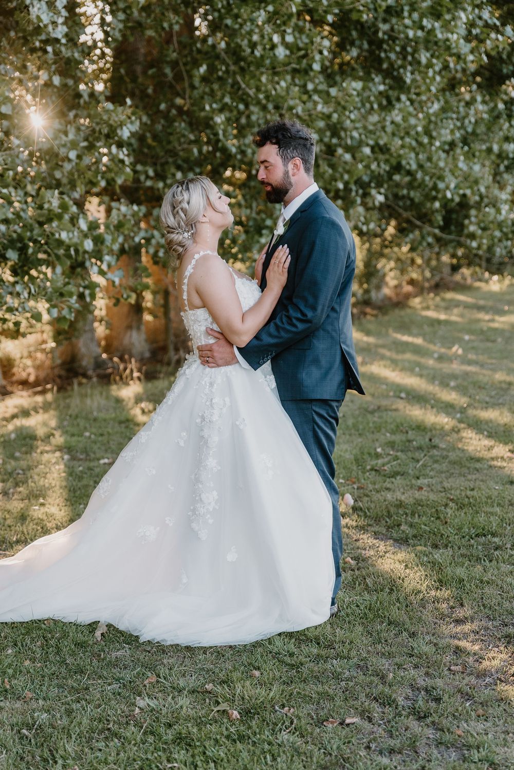Couple shares romantic dance on grassy lawn during golden hour wedding photography.