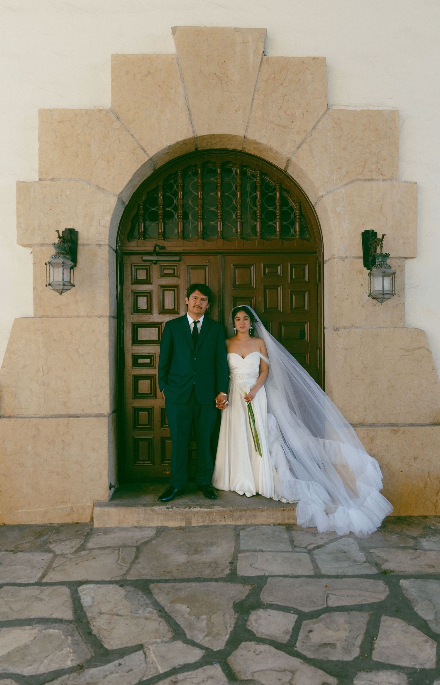 A sequence of wedding photos showing a couple posing against a rustic stone wall with green wooden doors and sconces.