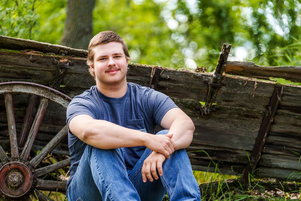 Casual outdoor portrait with person sitting on rustic wooden structure.