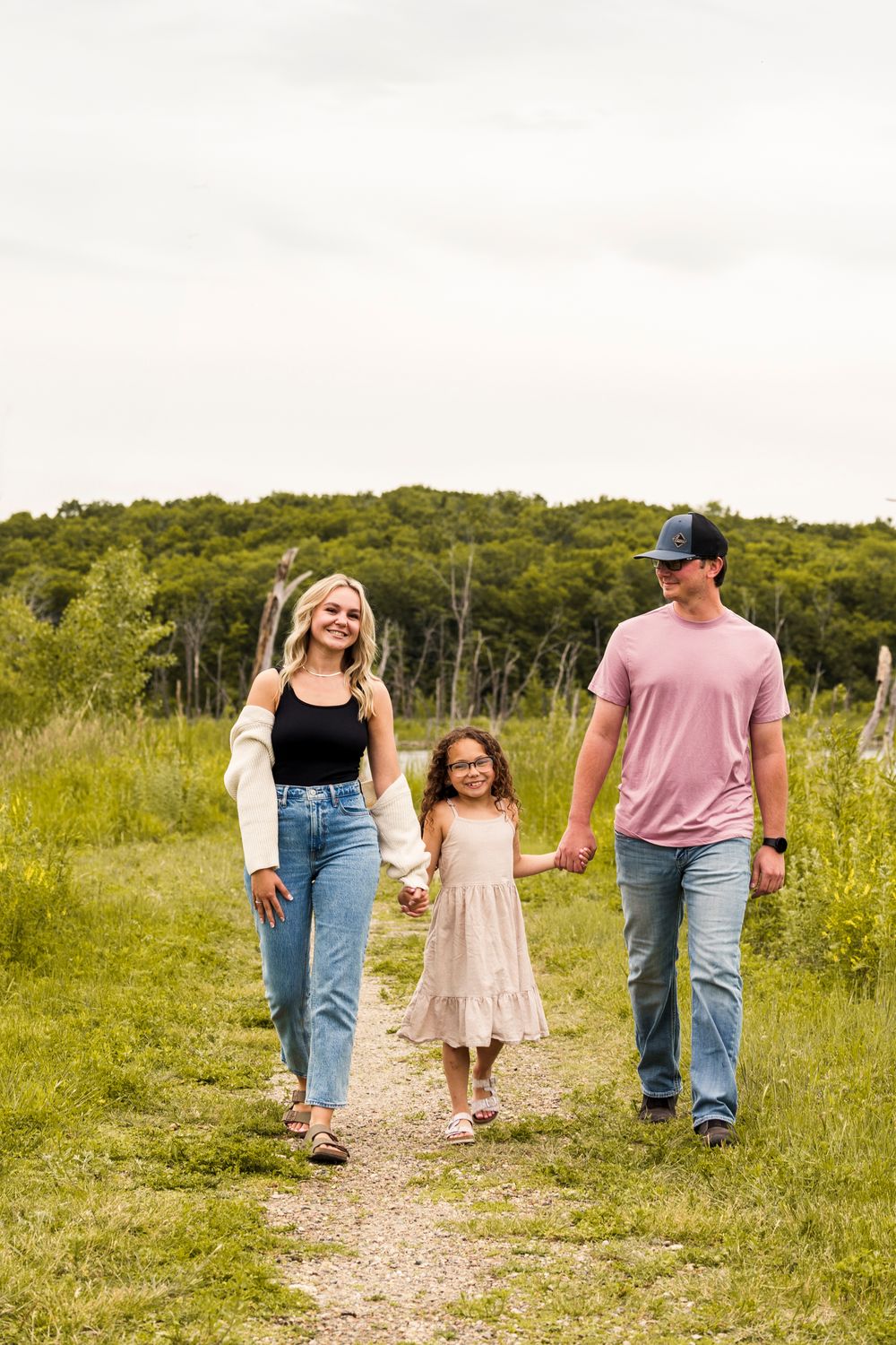 A family walking together on a dirt trail surrounded by lush green hills.