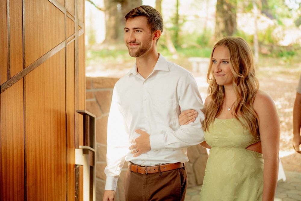 A couple laughs and embraces in a rustic wooden cabin filled with warm natural light.