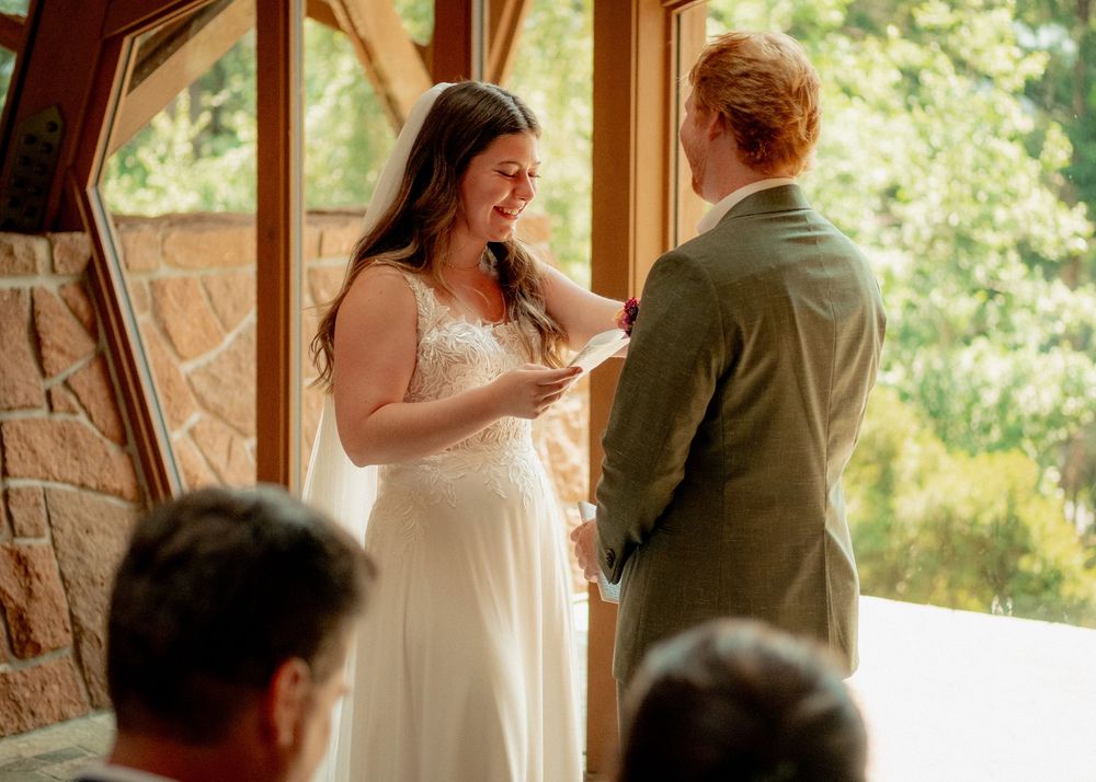Wedding ceremony couple sharing a tender moment in a rustic indoor venue with wooden panels.