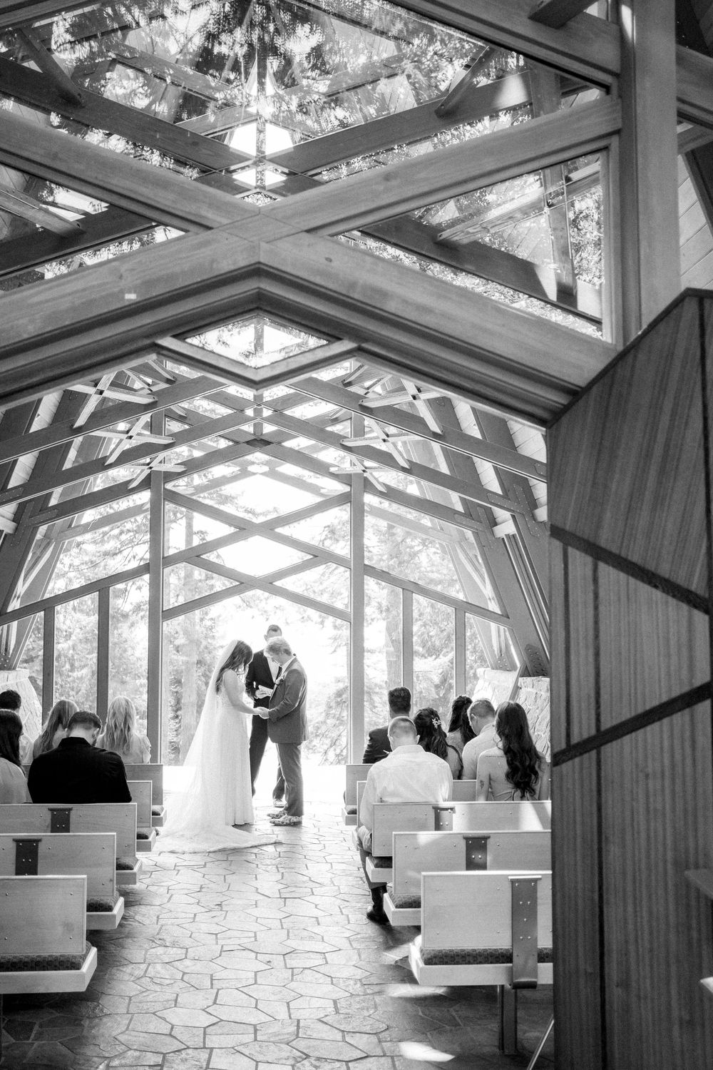 Modern glass-ceiling chapel interior with geometric patterns and white seating for wedding ceremony.