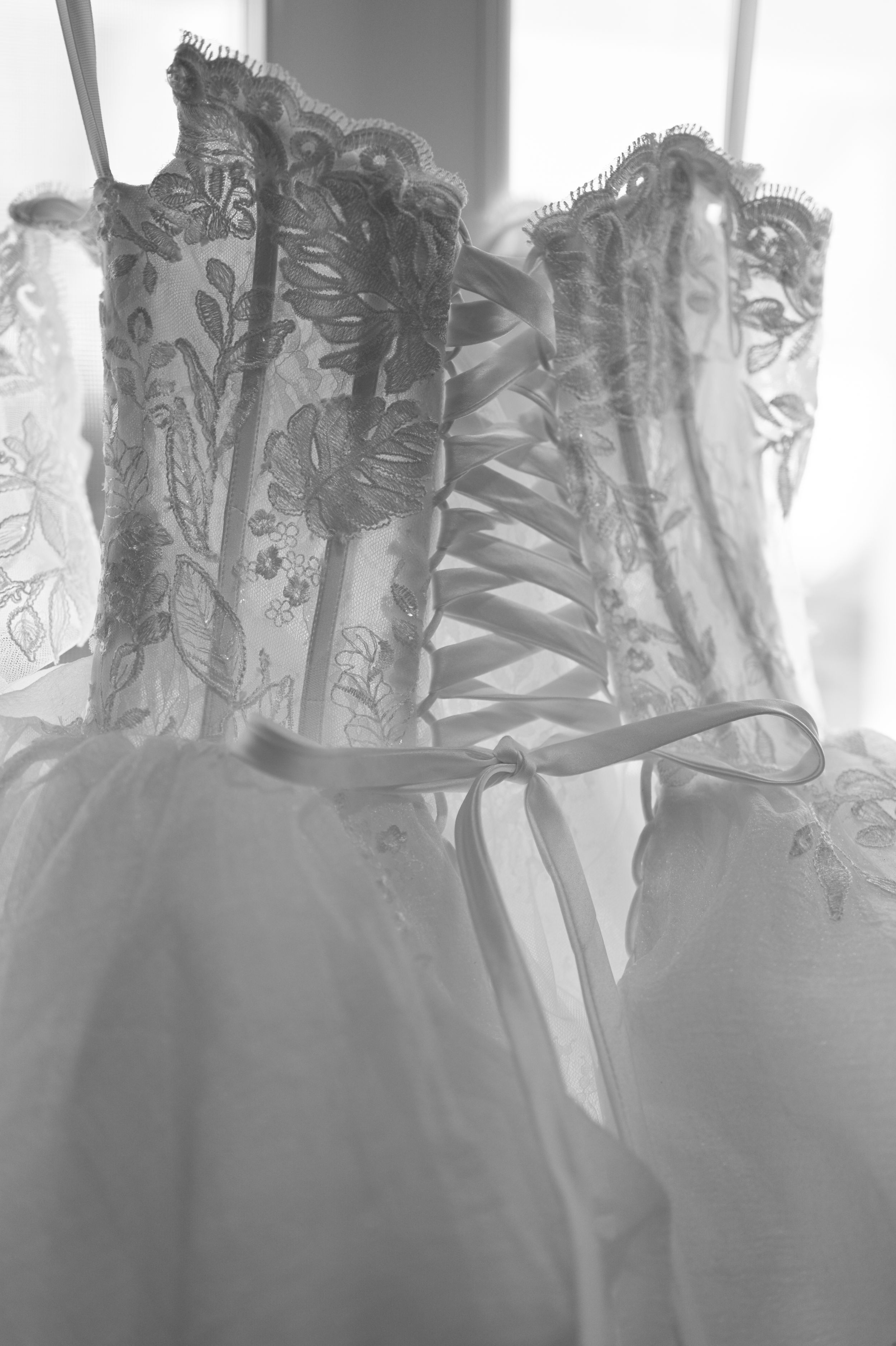 Close-up of an elegant white wedding dress corset with intricate lace detailing and ribbon lacing up the back.
