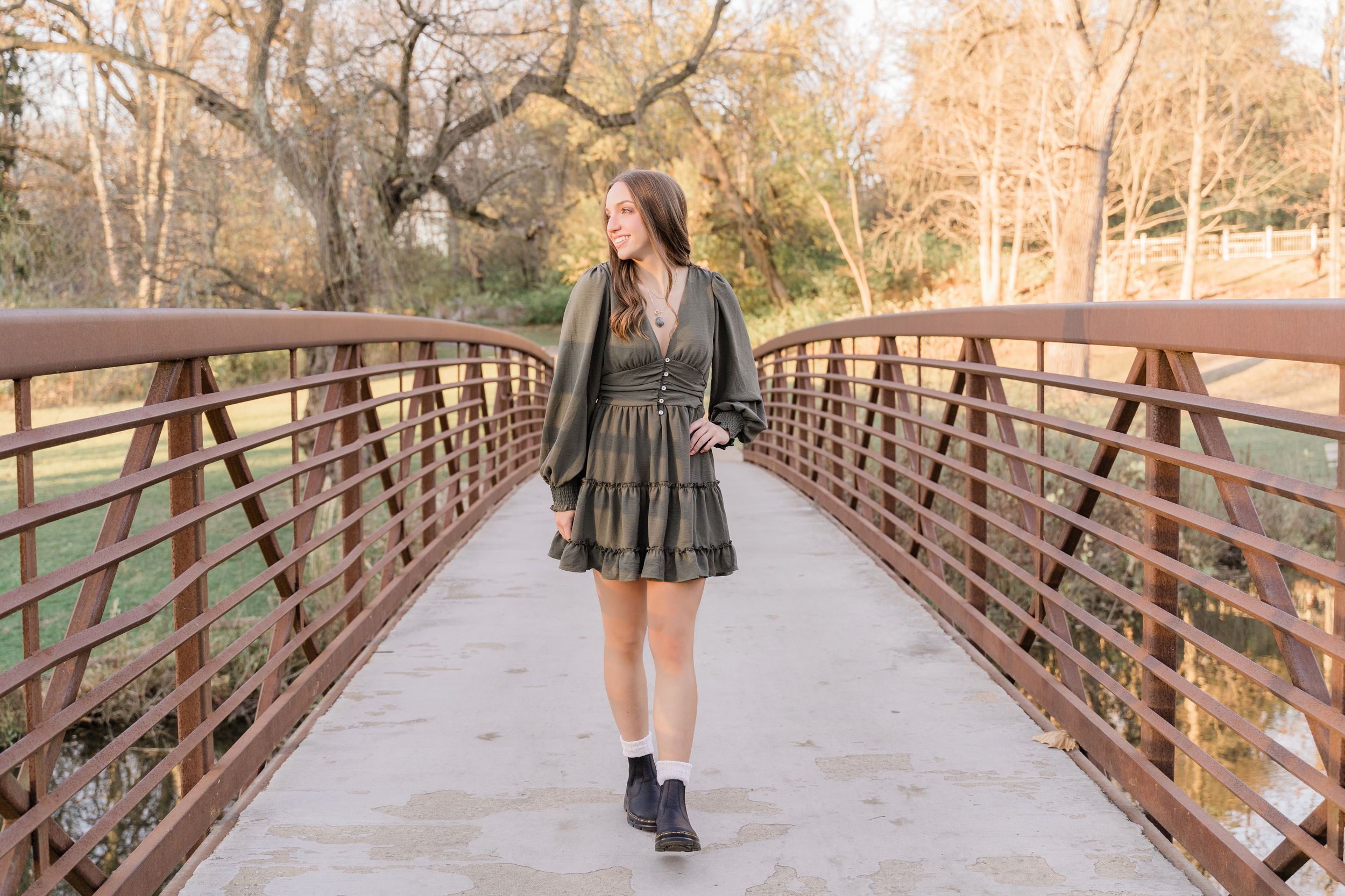 A scenic wooden footbridge walkway stretches through autumn trees in a tranquil park setting.