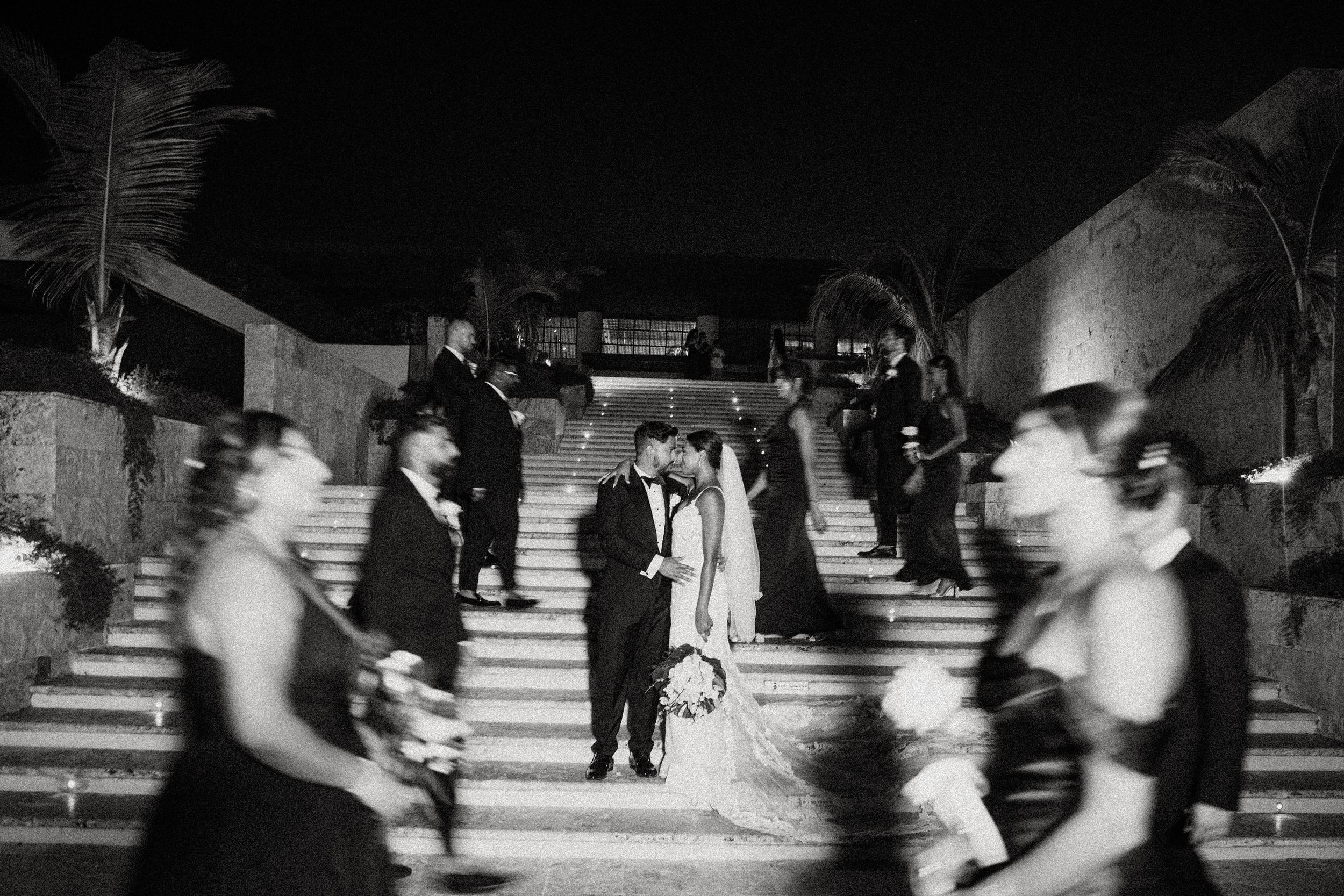 Black and white motion blur captures movement across stairs in an artistic wedding shot.
