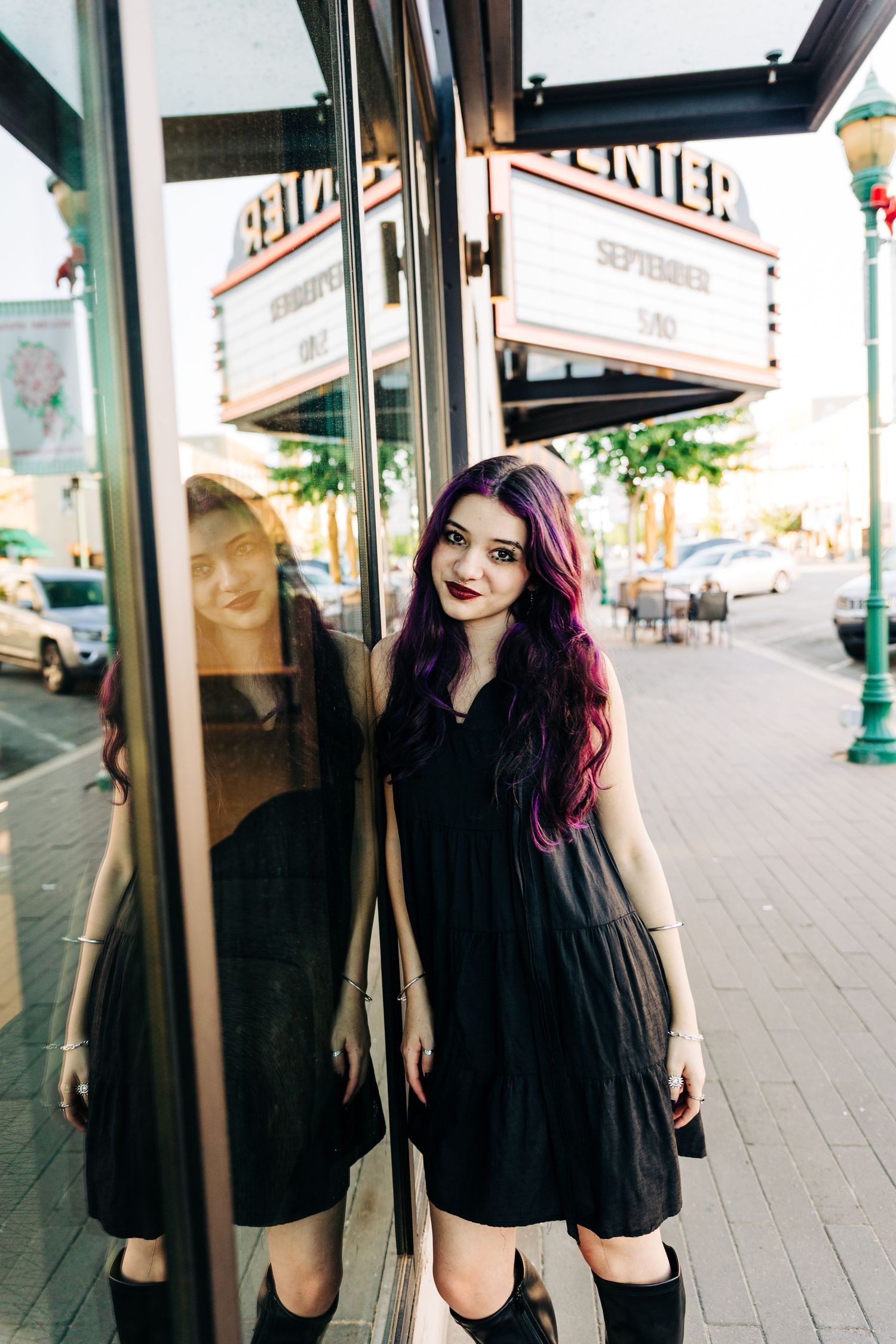 Four photos of someone in a black dress posing playfully against a storefront window on a sunny urban street.