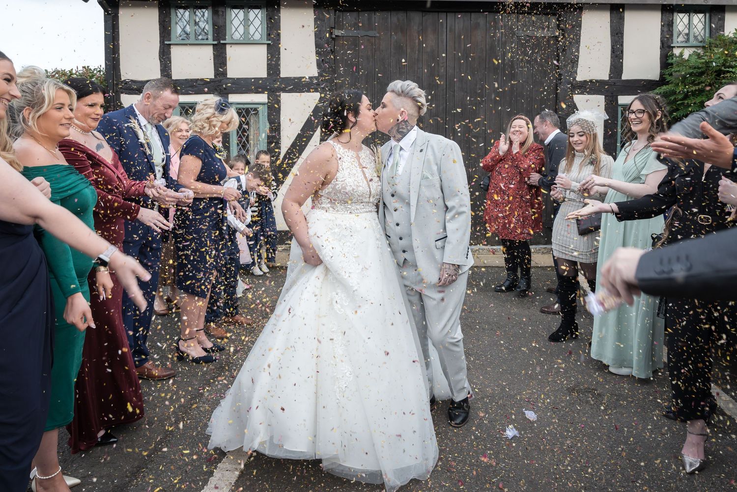 Guests shower the happy newlyweds with confetti outside a Tudor-style building during their wedding celebration.