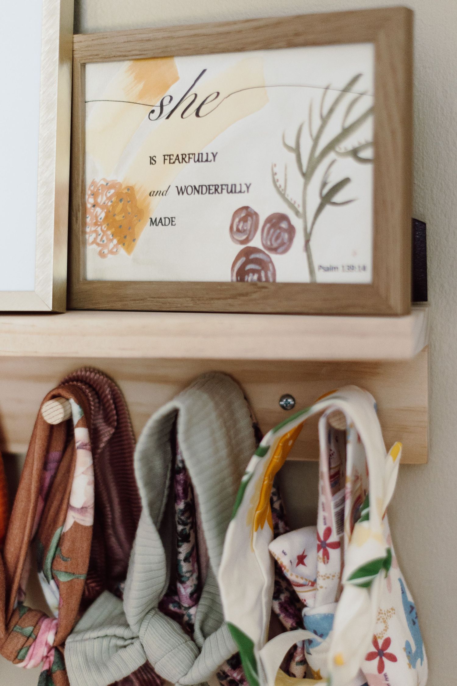 Wooden shelf displaying decorative text art and baby clothing items.