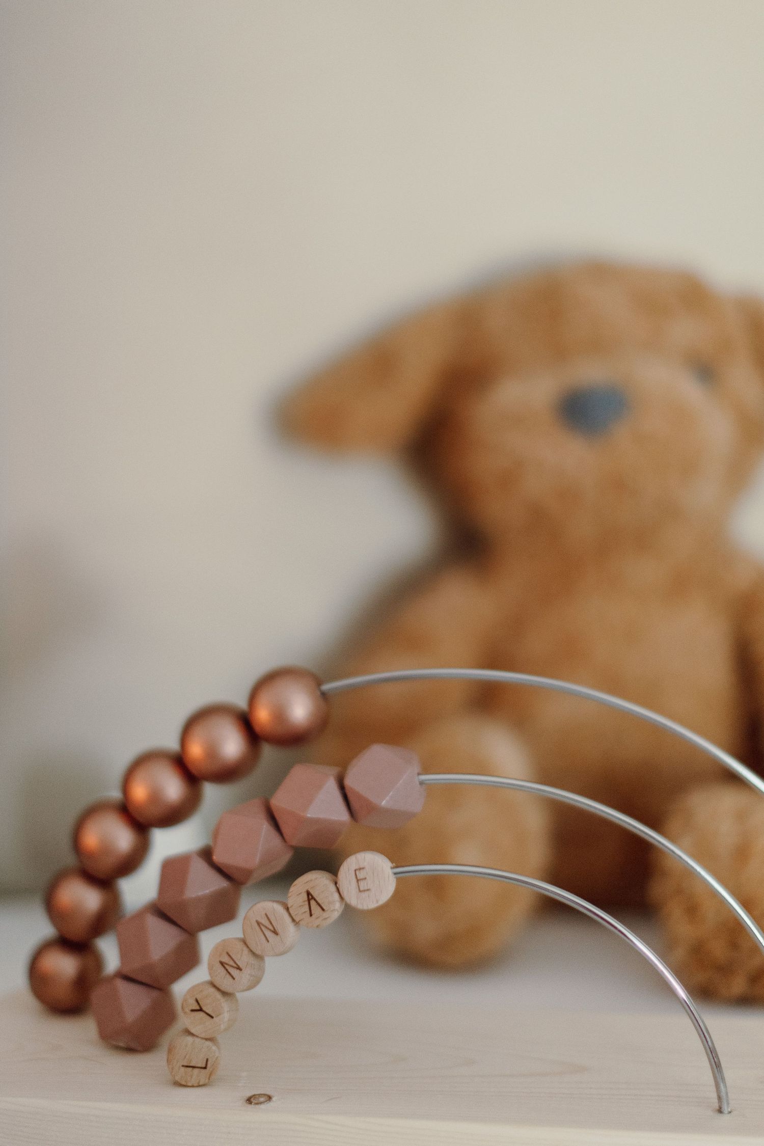 Decorative wooden beads arranged in an arch shape with text spelling out a word.