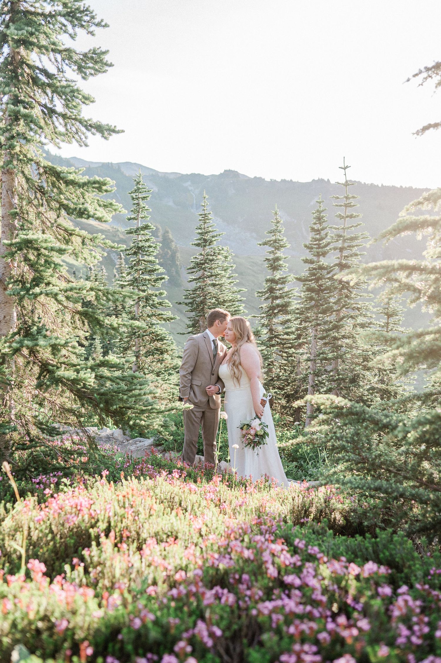 Bride and Groom at sunrise in Mt. Rainier National Park, surrounded by wildflowers. Photo by Washington Elopement Photographer, Pine + Vow.