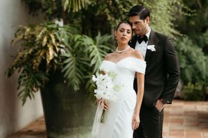 A bride and groom share an intimate moment in a lush garden setting during their wedding celebration.