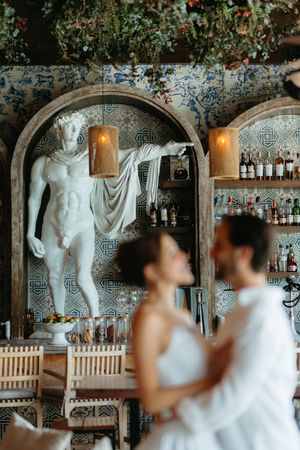 A series of wedding photos showing a couple at a bar decorated with classical white statues and elegant decor.
Italy wedding photographer