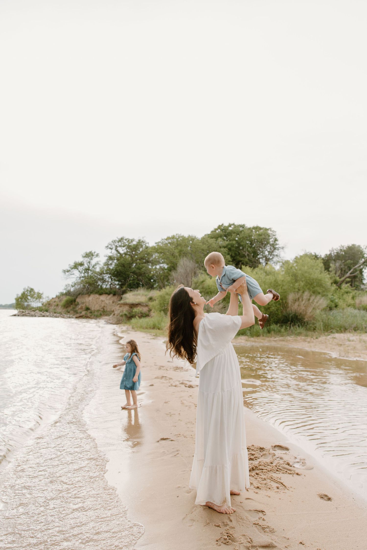 Family walking along beach shoreline at sunset.