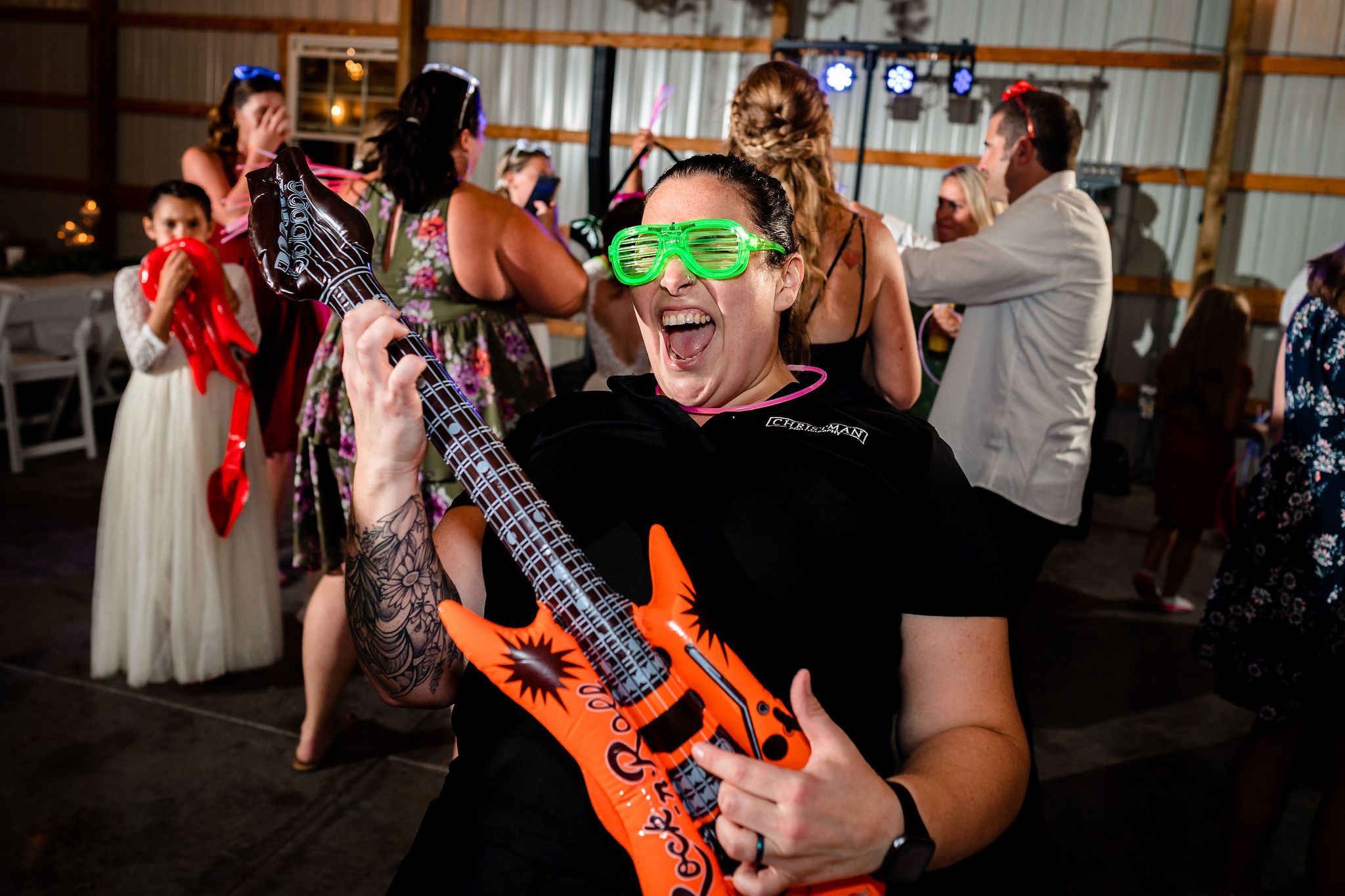Wedding reception party with guests playing inflatable air guitars on the dance floor.