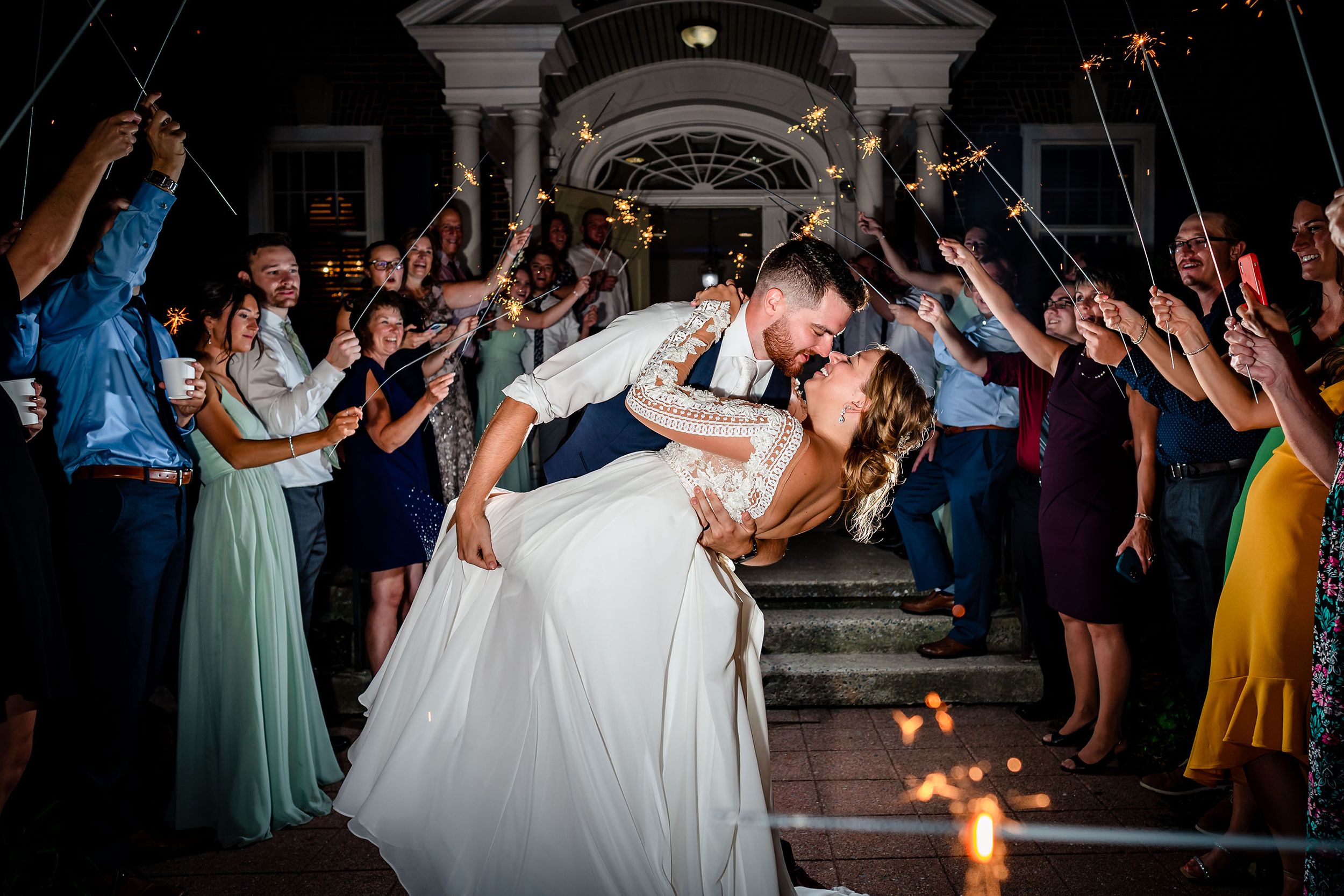 Energetic dance floor celebration during an elegant outdoor evening wedding reception.