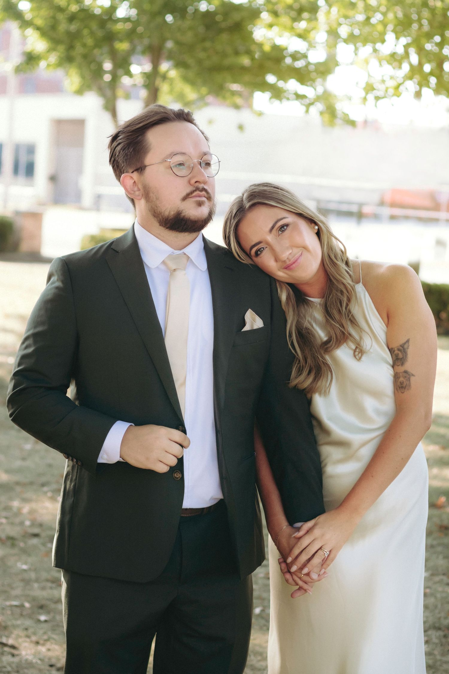 Playful wedding portraits with couple in formal attire under trees.