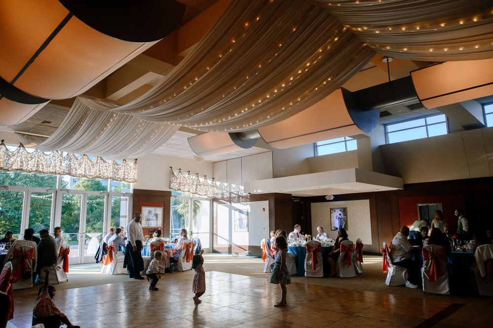 Indoor venue with string lights hanging from ceiling while people gather for a social event in a large open space.