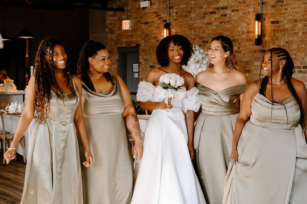 Wedding party in light gray dresses dancing and celebrating together at a reception.