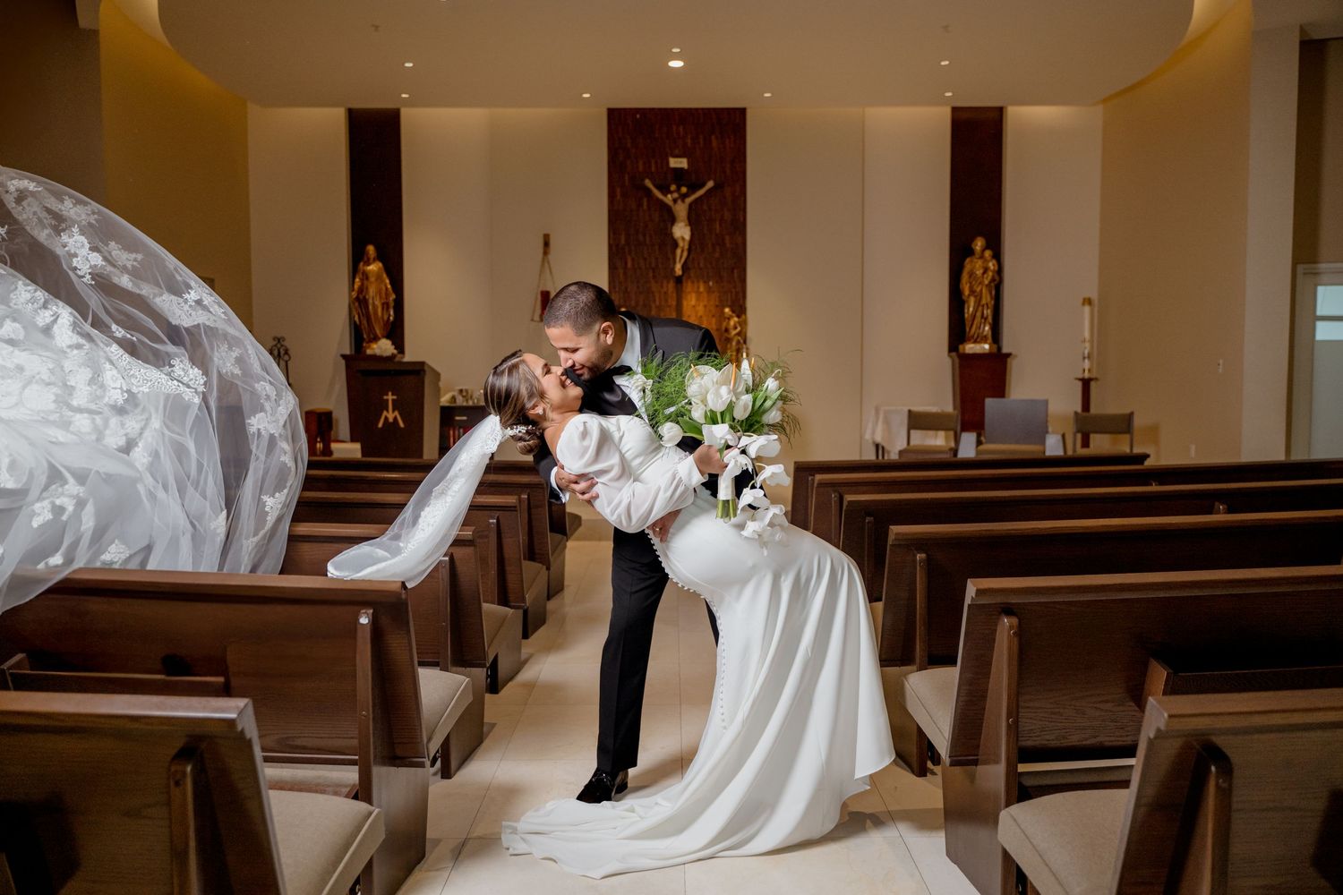 Wedding couple shares an intimate moment in church with sunlight streaming through stained glass windows.