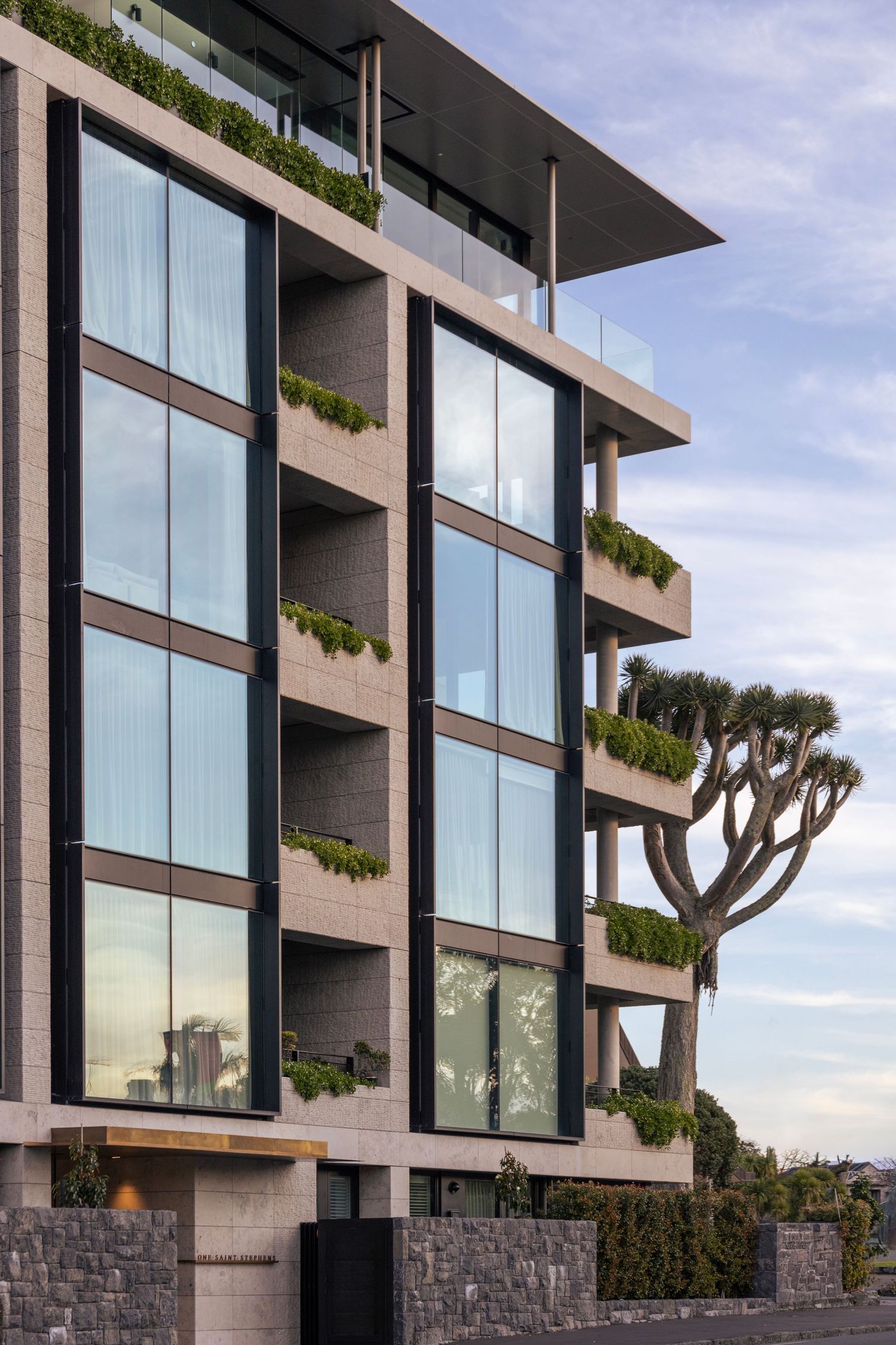Modern concrete building with wide glass panels and rows of integrated green planters.