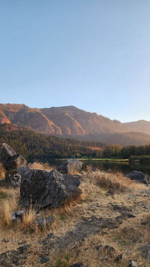 Sunlit mountain landscape with rocky terrain and open blue sky.