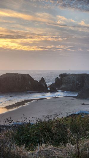 unset along the Oregon Coast with sea stacks and dramatic clouds.