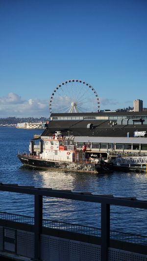 Seattle waterfront with ferry and Ferris wheel on a clear day.